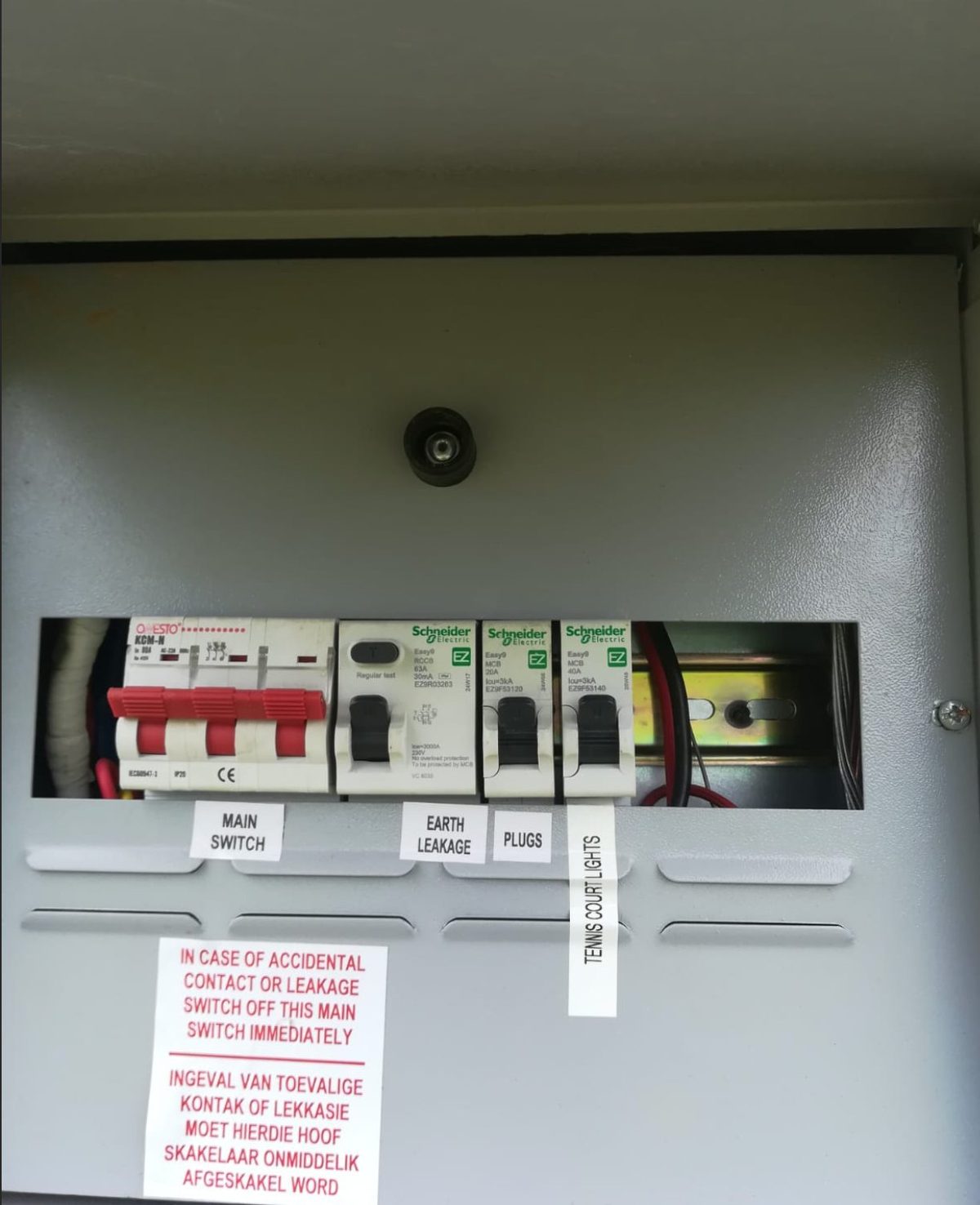 Labelled electrical distribution board commissioned and handed over by NineCourts — clearly marked Main Switch, Earth Leakage, Plugs and Tennis Court Lights