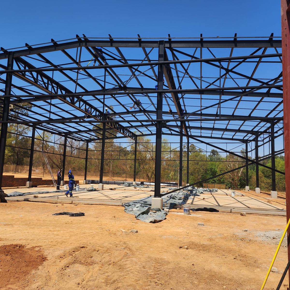 Steel framework of a NineCourts padel court build under construction against a clear blue sky