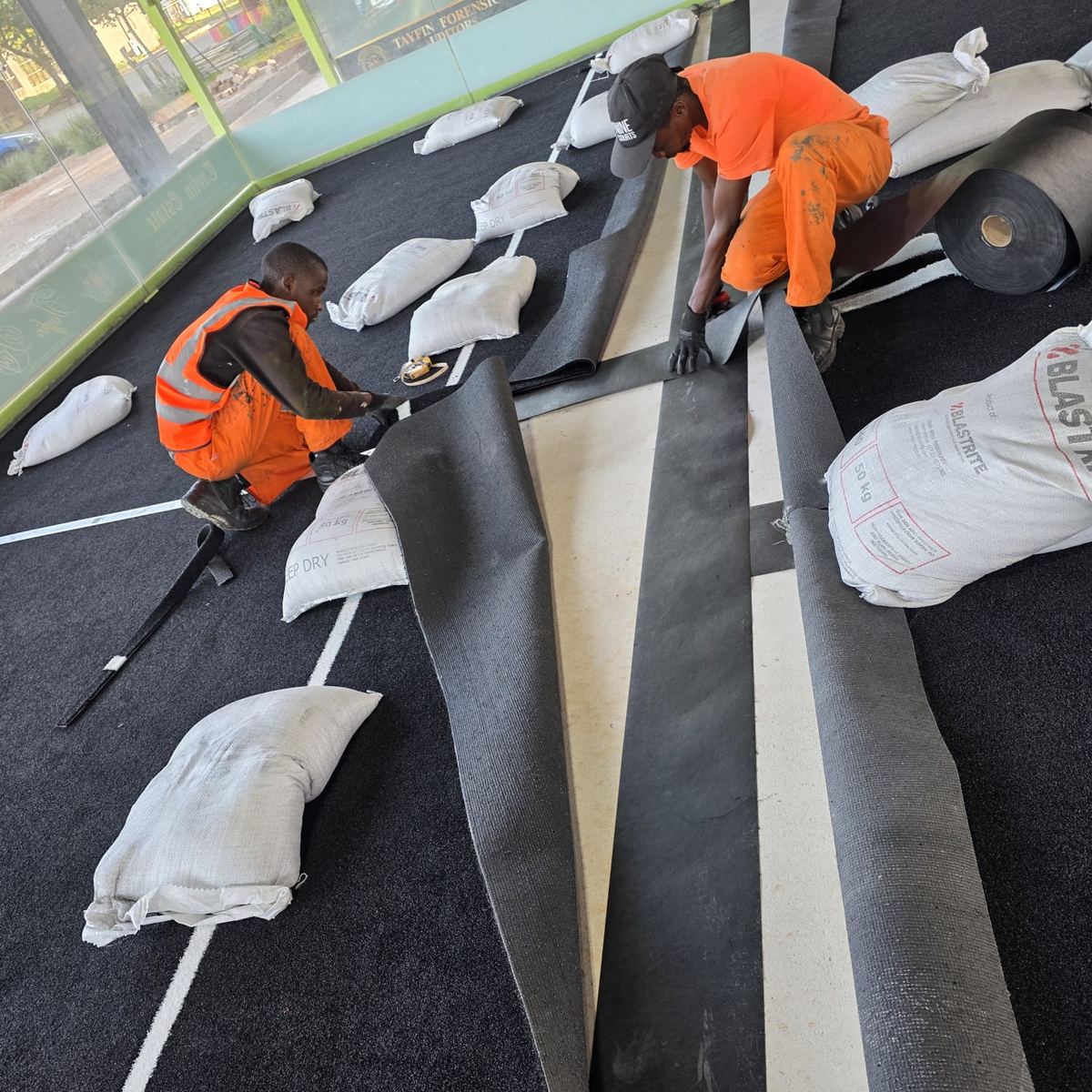 NineCourts crew laying padel-specific astro turf with sandbags during installation