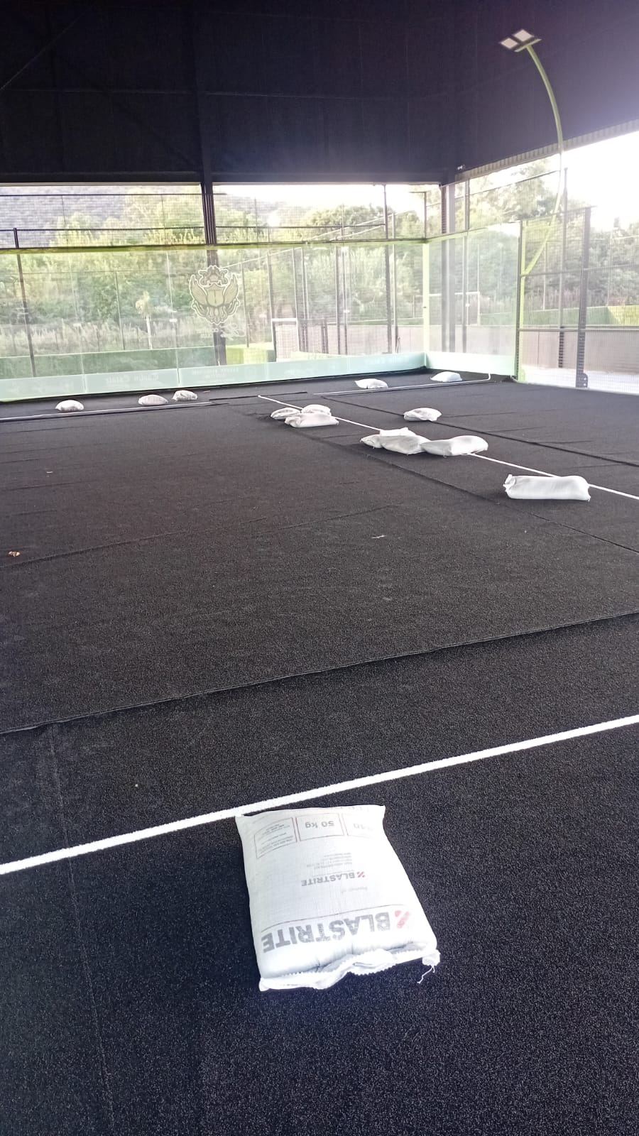 New astro turf rolled out on a NineCourts padel court during a replacement installation