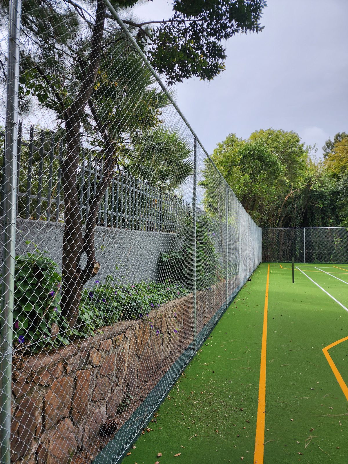 New chain link fencing installed along the stone-walled perimeter at the Sandhurst court