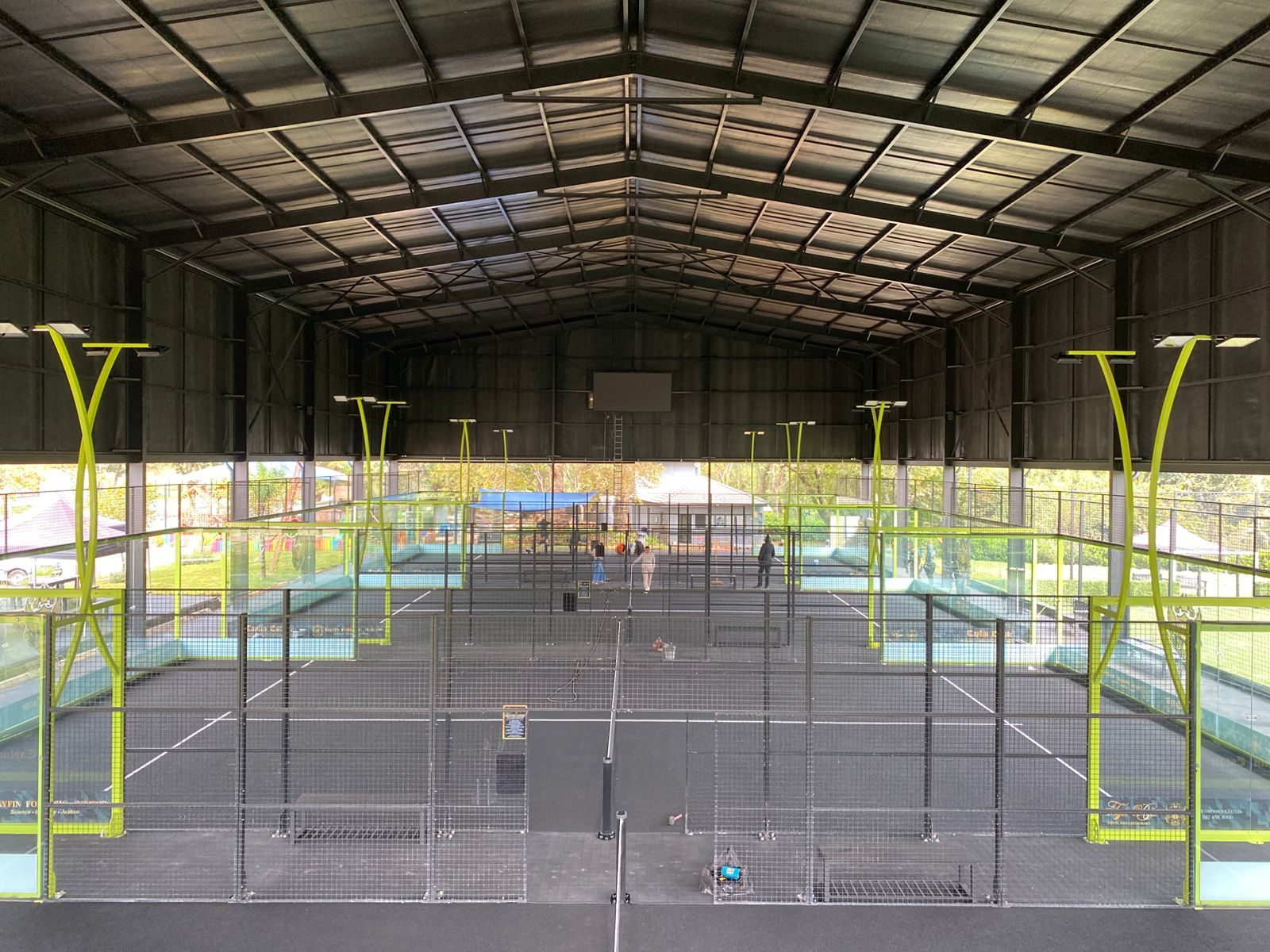 Tayfin Country Club padel facility — finished black padel courts under a lime-green steel canopy by NineCourts
