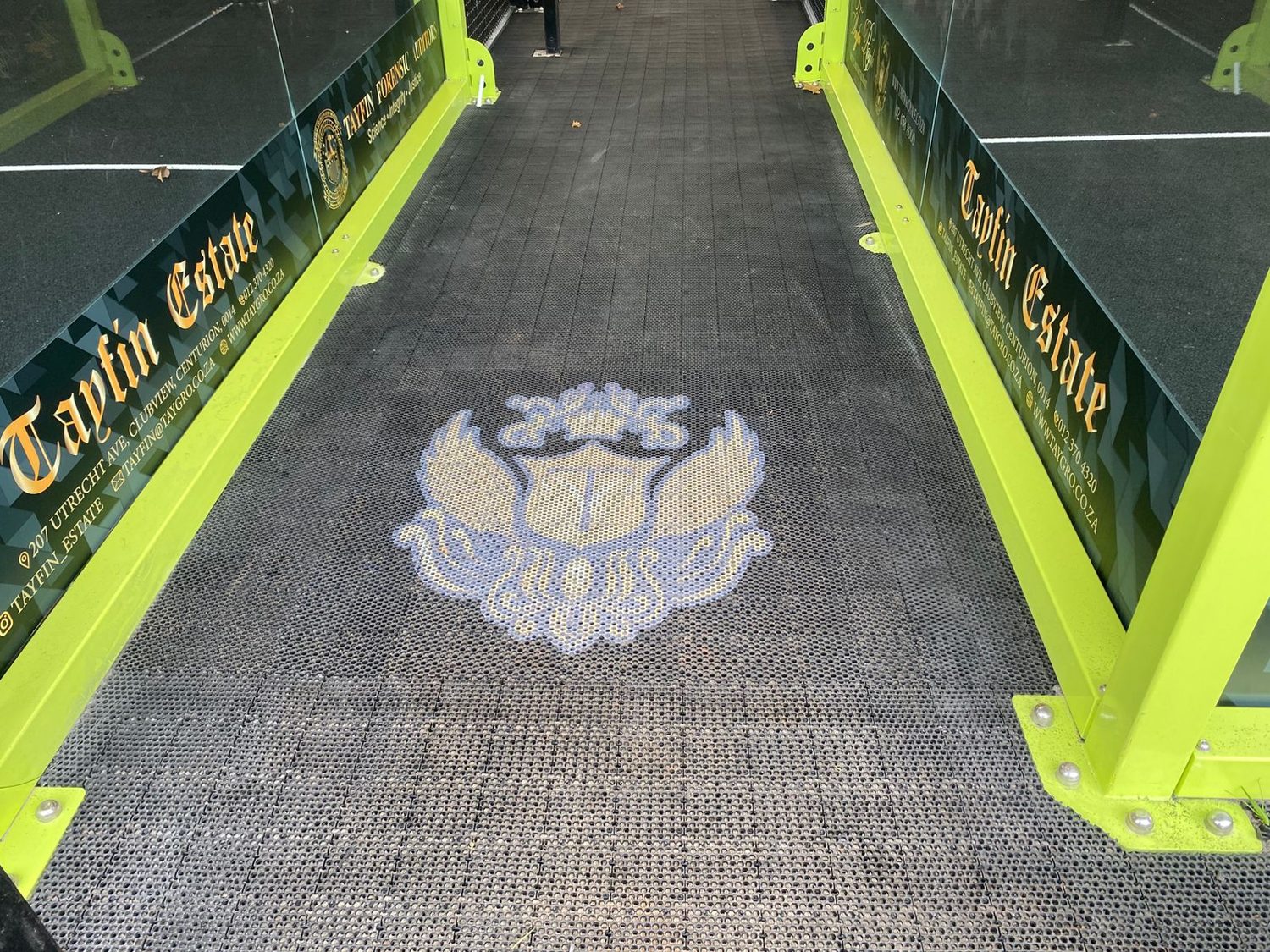 Tayfin Estate logo integrated into the InterLock Tiling at the entrance to a Tayfin Country Club padel court